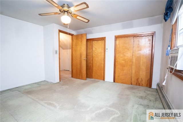 unfurnished bedroom with a ceiling fan, carpet, a baseboard heating unit, and two closets