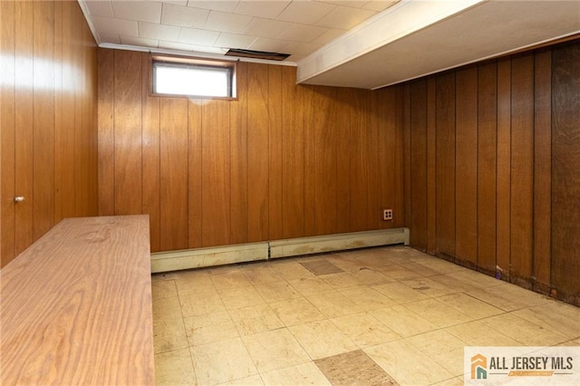 below grade area with a baseboard heating unit, light floors, and wood walls