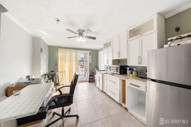 kitchen with ornamental molding, appliances with stainless steel finishes, light tile patterned floors, and white cabinets