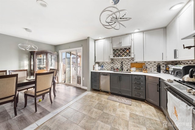 kitchen featuring stainless steel dishwasher, gray cabinets, sink, and hanging light fixtures