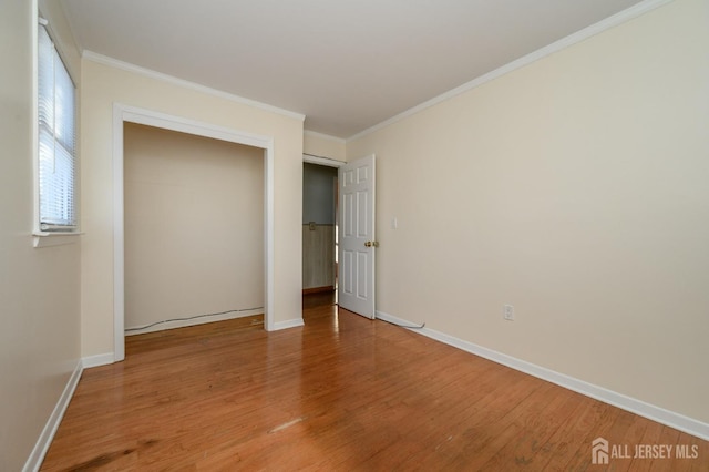 unfurnished bedroom with hardwood / wood-style flooring, crown molding, and a closet