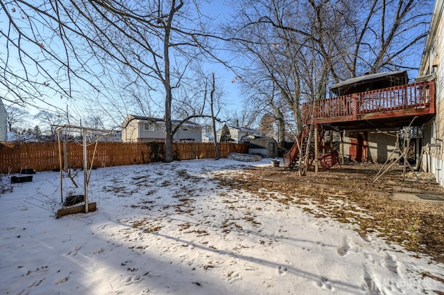 yard layered in snow featuring a shed and a deck