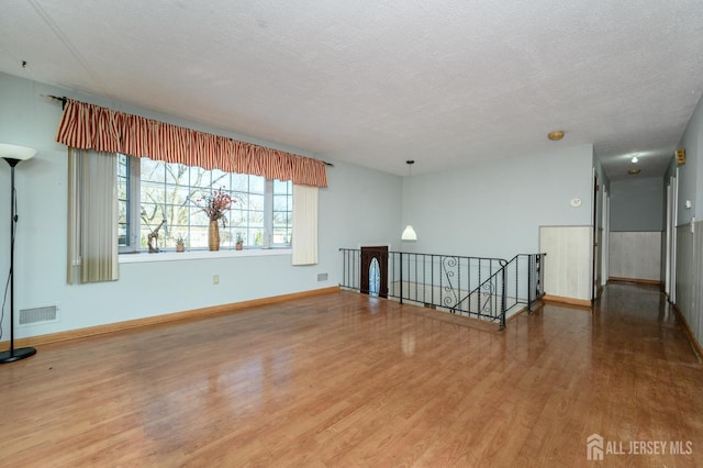 unfurnished room featuring hardwood / wood-style flooring and a textured ceiling