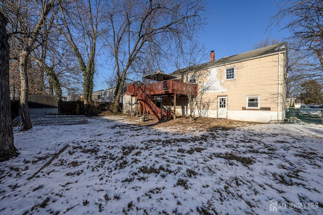 snow covered back of property featuring a deck