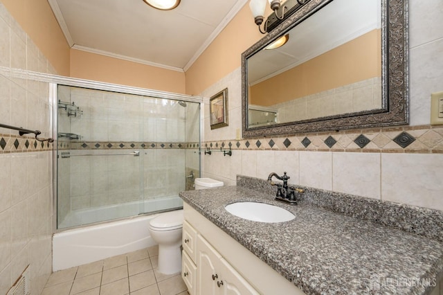 full bathroom featuring tile patterned floors, toilet, combined bath / shower with glass door, tile walls, and vanity