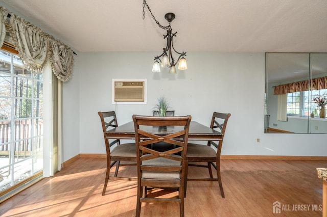 dining space with an AC wall unit, an inviting chandelier, and light wood-type flooring