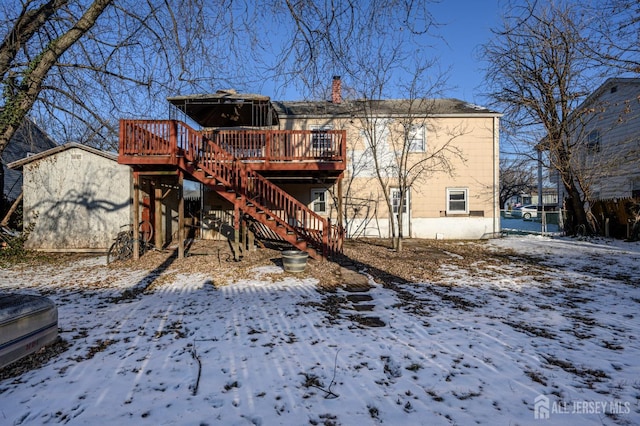 snow covered rear of property with a deck