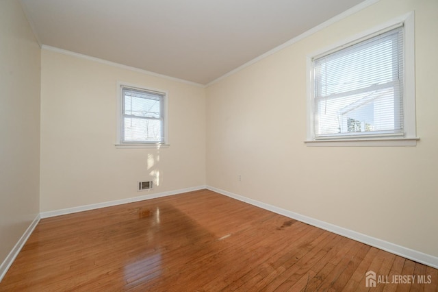 empty room with ornamental molding and hardwood / wood-style floors