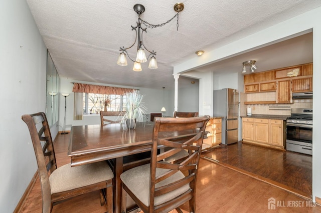 dining room featuring dark hardwood / wood-style flooring, a textured ceiling, and ornate columns