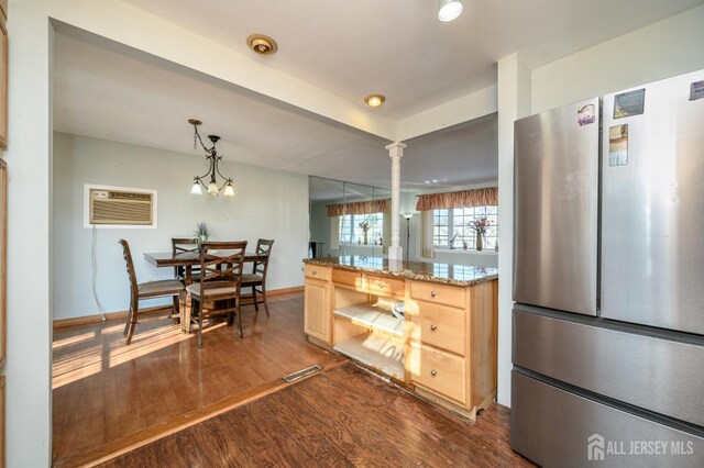 kitchen featuring light brown cabinetry, light stone counters, an AC wall unit, stainless steel fridge, and pendant lighting