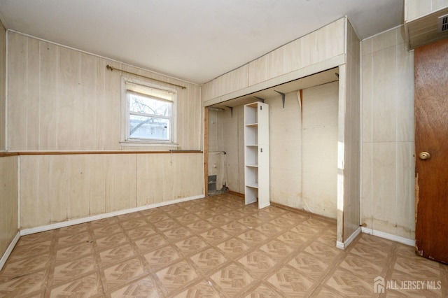 unfurnished bedroom with parquet floors, a closet, and wood walls