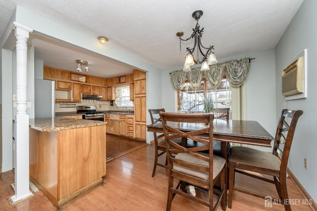 kitchen featuring sink, a textured ceiling, stainless steel stove, light hardwood / wood-style floors, and backsplash