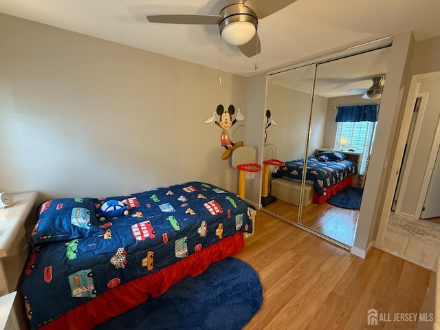 bedroom featuring a closet, wood finished floors, and ceiling fan
