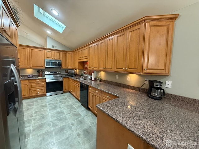 kitchen with brown cabinetry, visible vents, a sink, stainless steel appliances, and vaulted ceiling with skylight