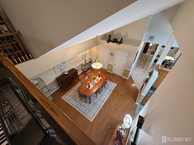 living area featuring visible vents, wood finished floors, baseboards, and high vaulted ceiling