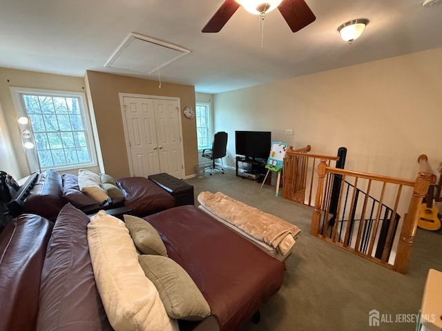 carpeted living room with attic access and a ceiling fan