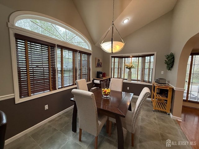dining space featuring tile patterned floors, plenty of natural light, baseboards, and arched walkways