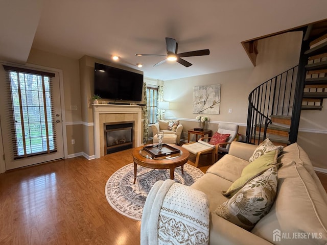living room with a wealth of natural light, wood finished floors, a ceiling fan, and a fireplace