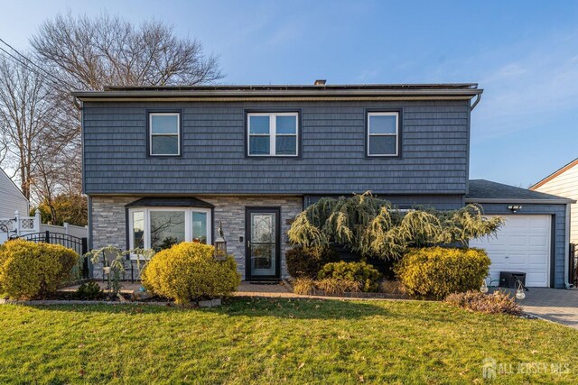 view of property featuring a garage and a front lawn