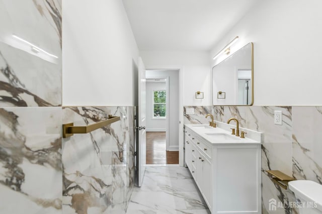 244 Lloyd Rd, Matawan, NJ 07747 - bathroom featuring marble look tile flooring, double vanity, tile walls, toilet, and wainscoting