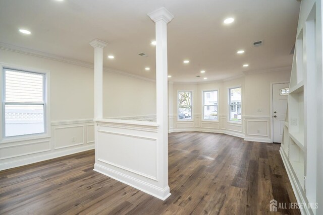 spare room featuring ornamental molding, visible vents, decorative columns, and dark wood finished floors