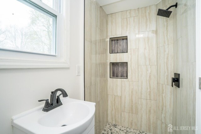 full bathroom featuring tiled shower and a sink