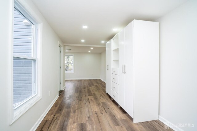 hall featuring dark wood-style flooring, baseboards, and recessed lighting
