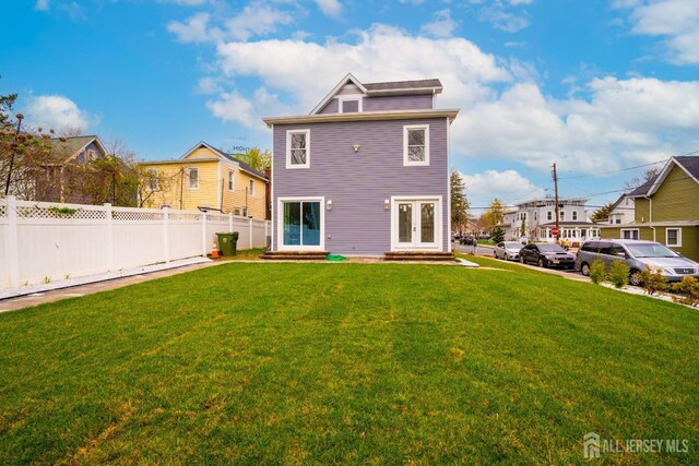 rear view of property with a lawn, fence, french doors, and entry steps