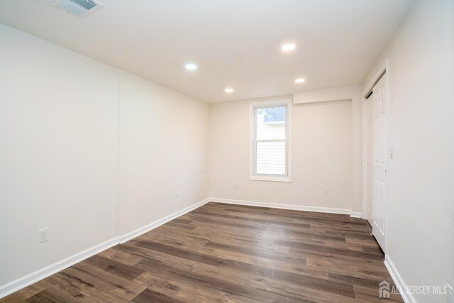 empty room with baseboards, visible vents, recessed lighting, and dark wood finished floors