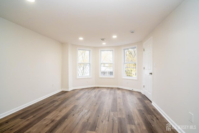 empty room with baseboards, dark wood-style floors, visible vents, and recessed lighting