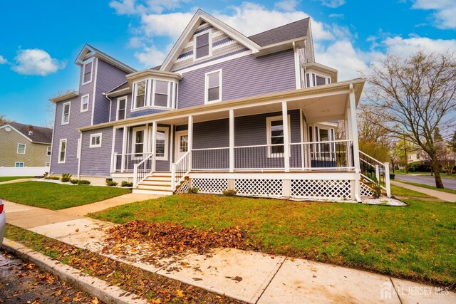 victorian house with a front yard and a porch