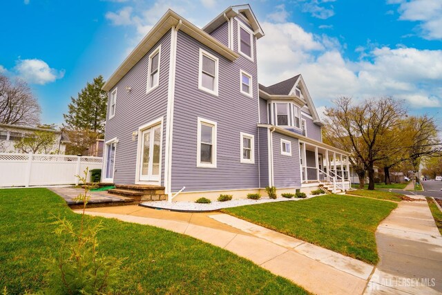view of home's exterior with a lawn, covered porch, and fence