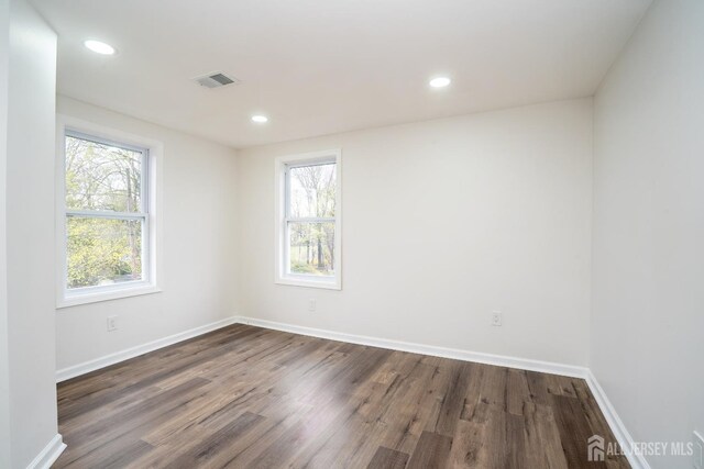 empty room with baseboards, dark wood-style floors, visible vents, and recessed lighting