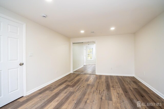 spare room featuring dark wood-style flooring, visible vents, baseboards, and recessed lighting