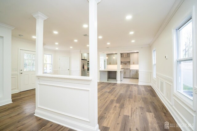 kitchen with crown molding, stainless steel fridge, a decorative wall, dark wood-type flooring, and ornate columns