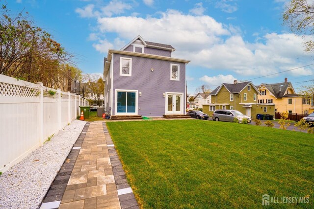 rear view of property with fence, entry steps, a residential view, french doors, and a yard