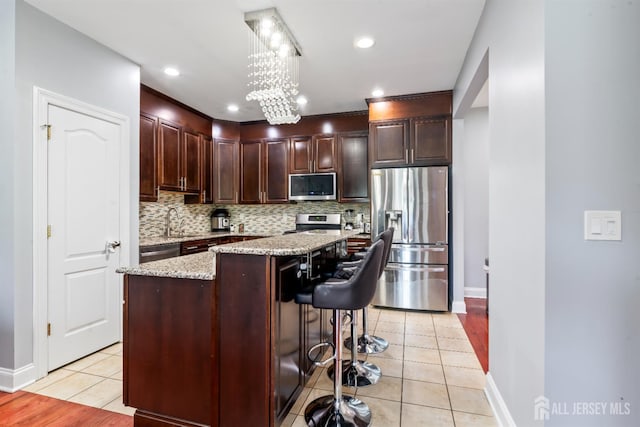 32 Cinder Rd Unit 22, Edison, NJ 08820 - kitchen with stainless steel appliances, light tile patterned floors, tasteful backsplash, a center island, and light stone counters