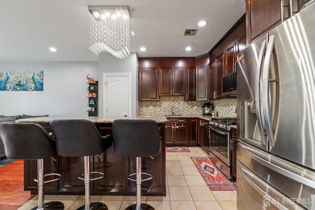 32 Cinder Rd Unit 22, Edison, NJ 08820 - kitchen featuring appliances with stainless steel finishes, a kitchen island, a kitchen breakfast bar, backsplash, and light tile patterned flooring