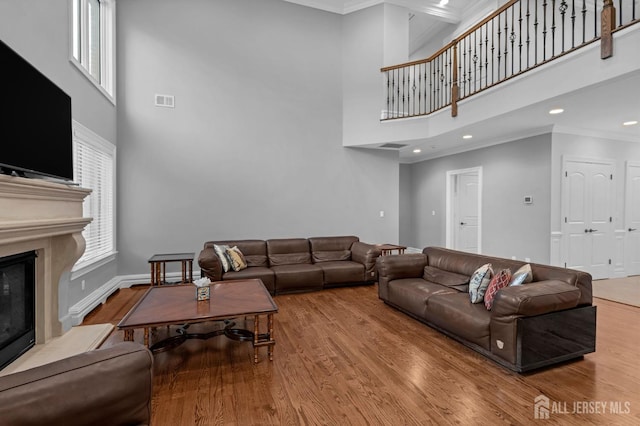 living area with a high ceiling, ornamental molding, and wood finished floors