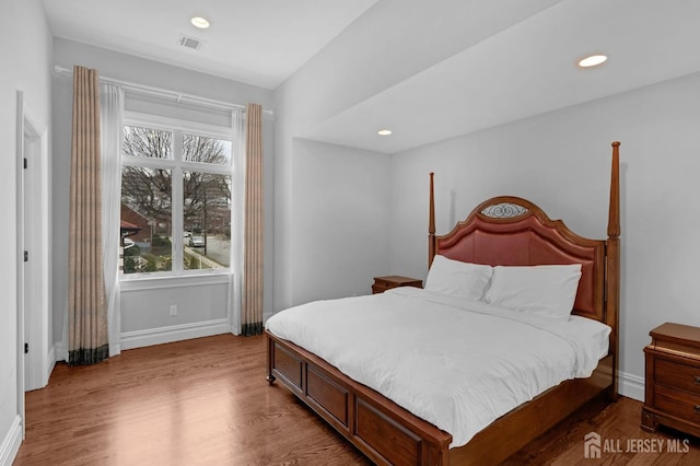 bedroom featuring baseboards, visible vents, multiple windows, and wood finished floors