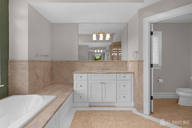 full bathroom featuring a garden tub, tile patterned floors, vanity, toilet, and an inviting chandelier