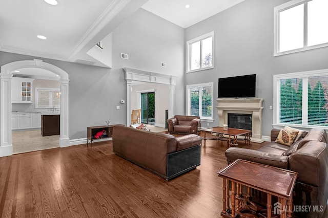living room featuring visible vents, decorative columns, a glass covered fireplace, and a high ceiling