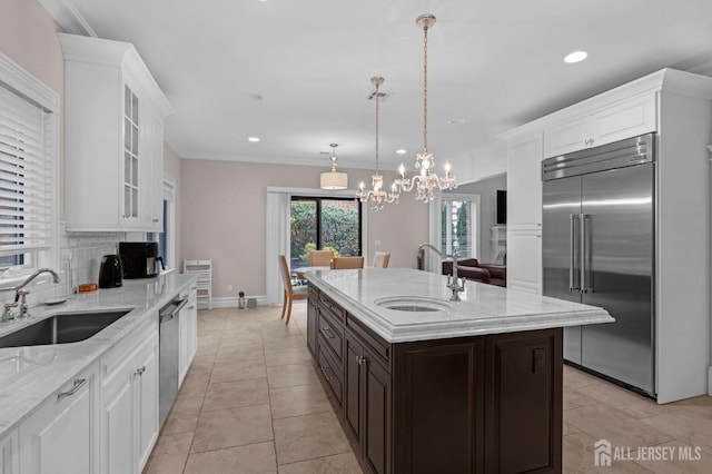 kitchen with a sink, glass insert cabinets, light stone countertops, and stainless steel appliances
