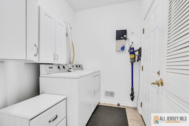 laundry area featuring baseboards, light tile patterned flooring, visible vents, washer and clothes dryer, and cabinet space