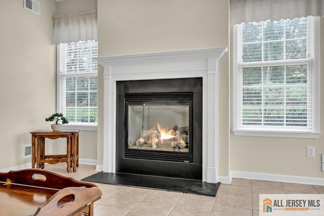 room details featuring visible vents, baseboards, and a glass covered fireplace