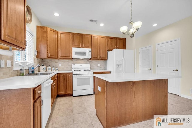 kitchen with a sink, visible vents, decorative backsplash, and white appliances