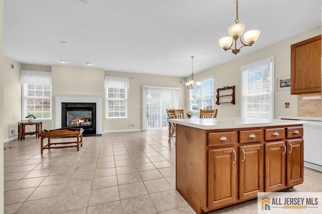 kitchen with brown cabinets, light countertops, pendant lighting, and an inviting chandelier