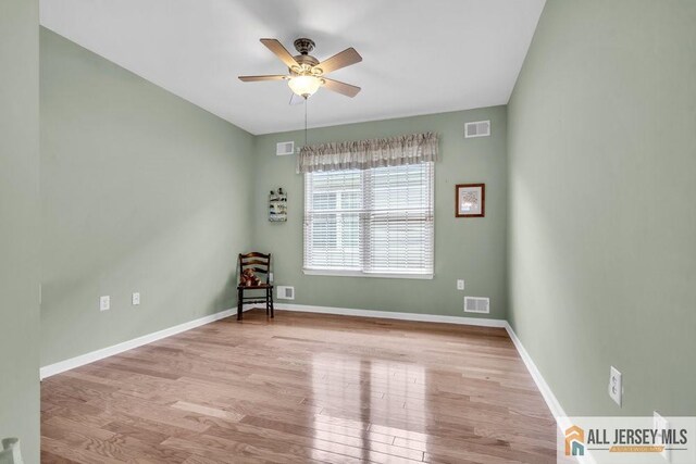 empty room with visible vents, baseboards, a ceiling fan, and wood finished floors