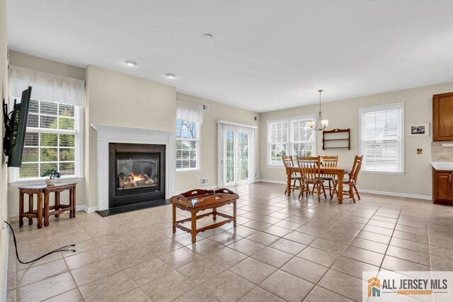 living area featuring plenty of natural light, a fireplace with flush hearth, and baseboards