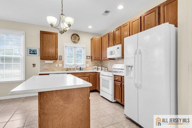 kitchen featuring light countertops, backsplash, a sink, and white appliances